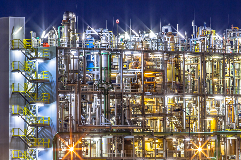 Night scene of detail of a heavy Chemical Industrial plant with mazework of pipes in twilight